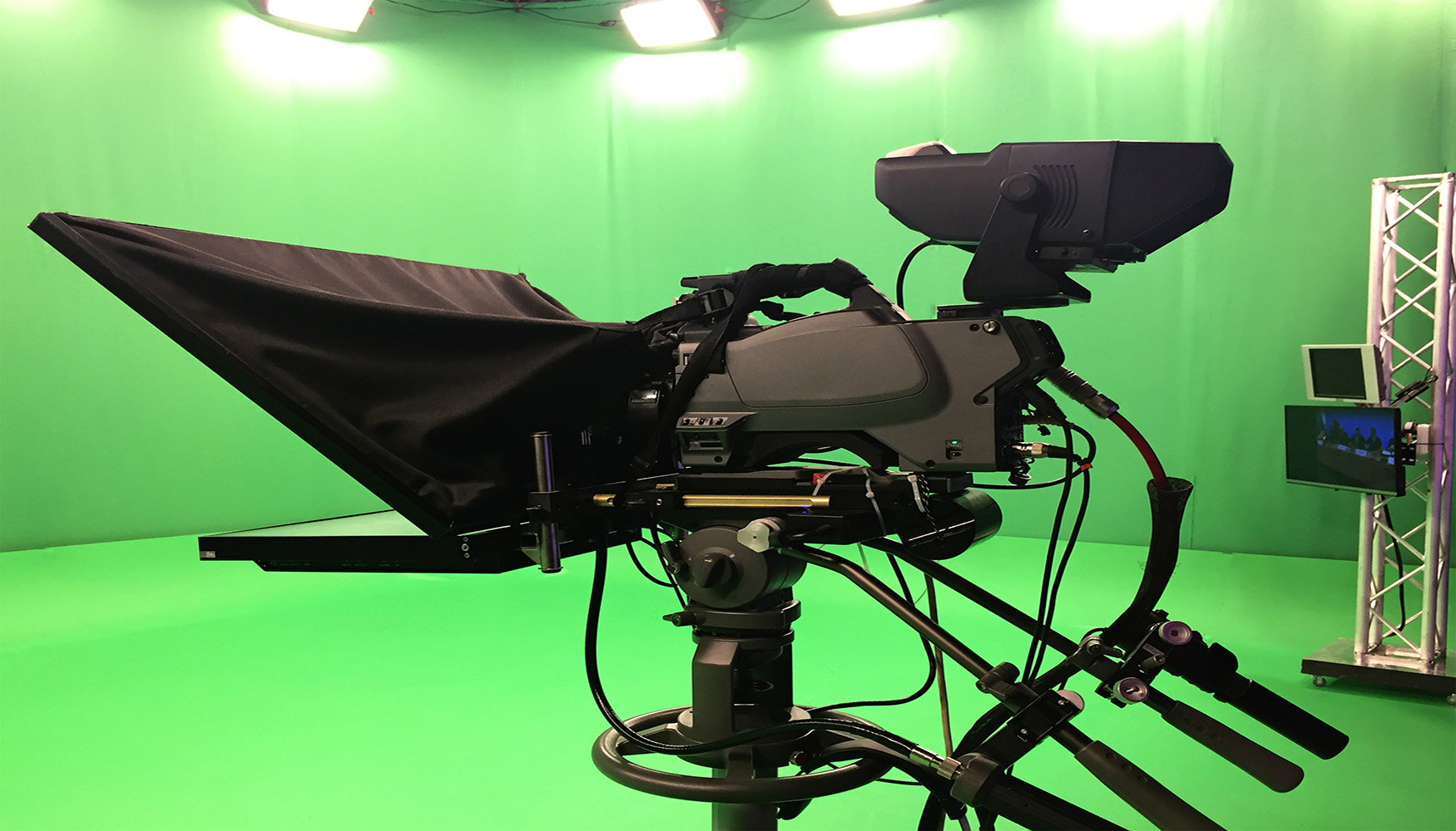 Modern empty green video recording and broadcasting studio with tv channel led screen and metalic stands, text prompter, lights on